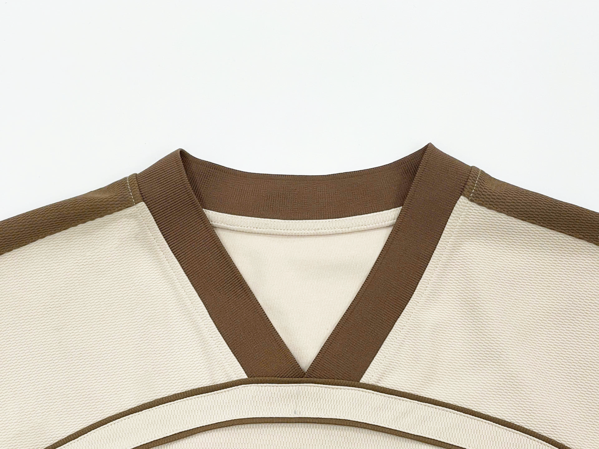 V-neck with thick brown trim, accented with an inner cream lining.