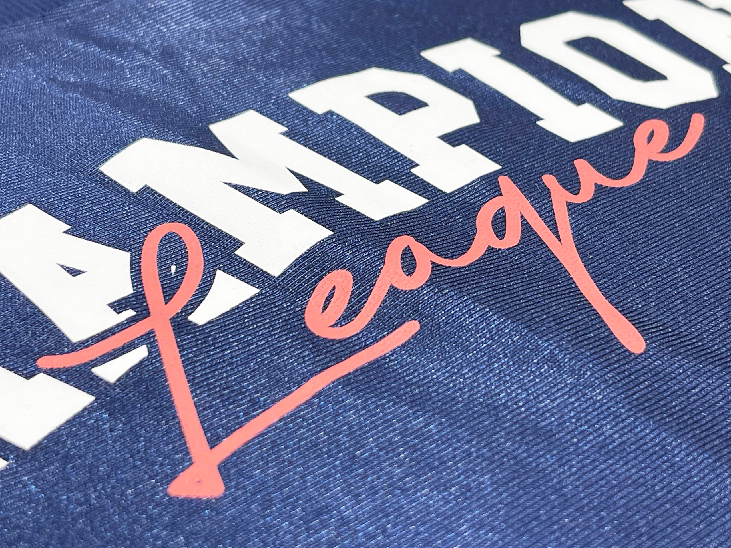 “CHAMPION League” uses dual-layer heat transfer, combining bold block letters with smooth script for contrast and depth.