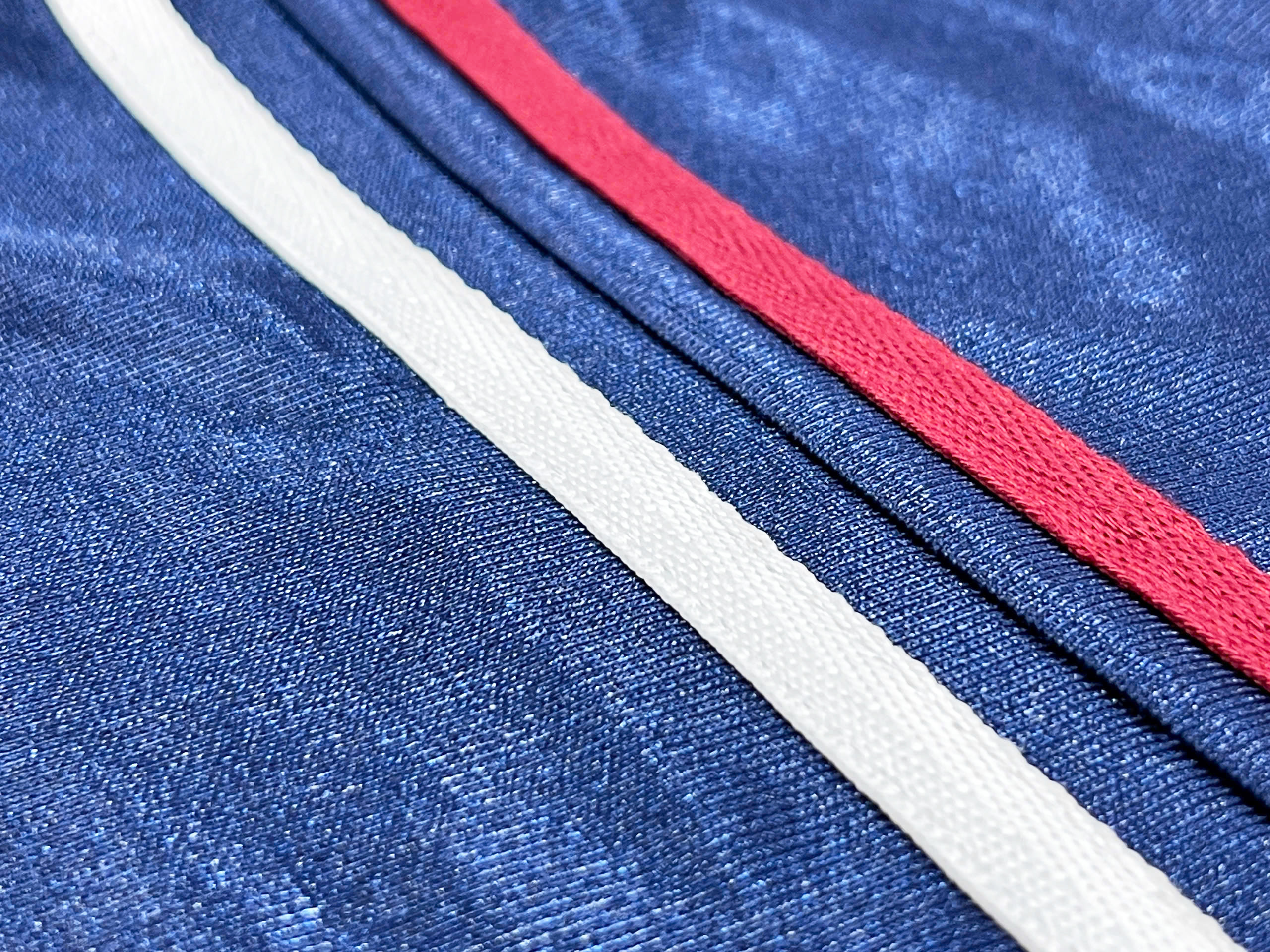 Twin contrast stripes in white and deep red run vertically along the back seam, offering a nod to vintage athletic wear. 