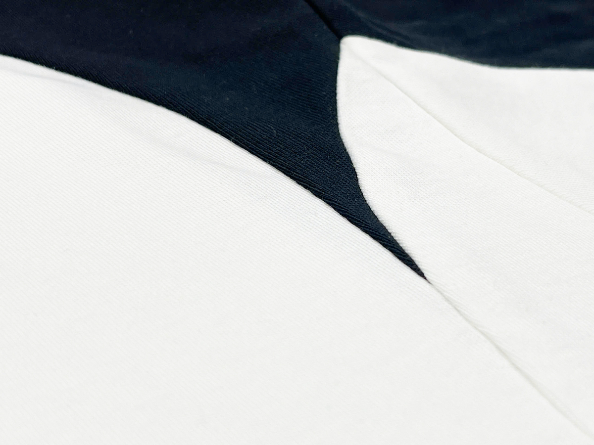 Distinctive panel construction with curved black inserts along the shoulders and back creates a dynamic, layered visual effect.